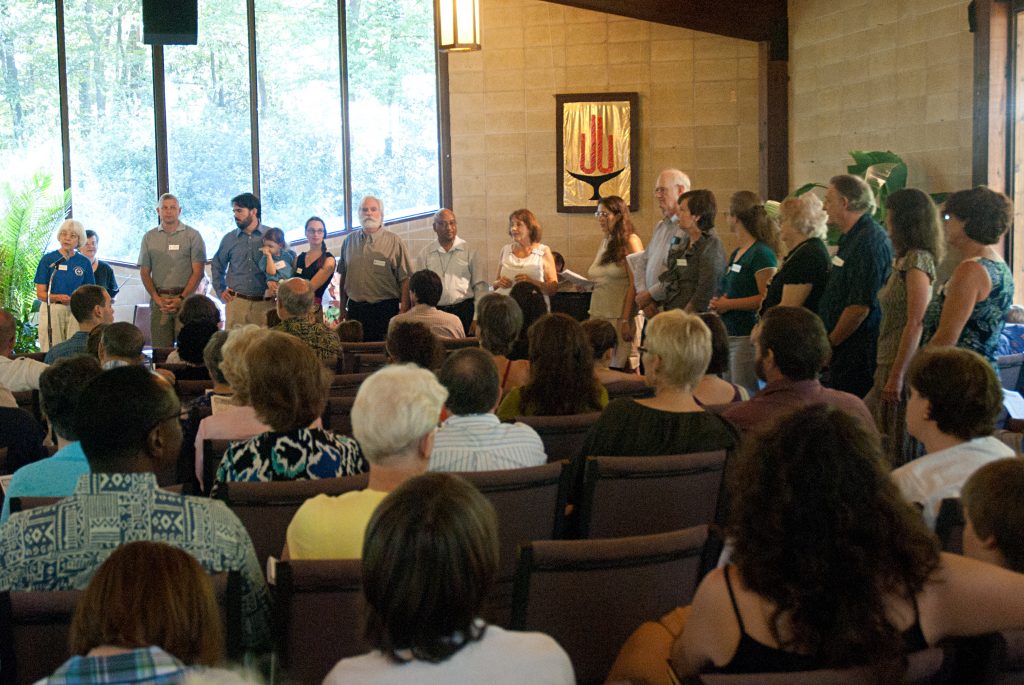 people sitting watching as new members line up to be welcomed